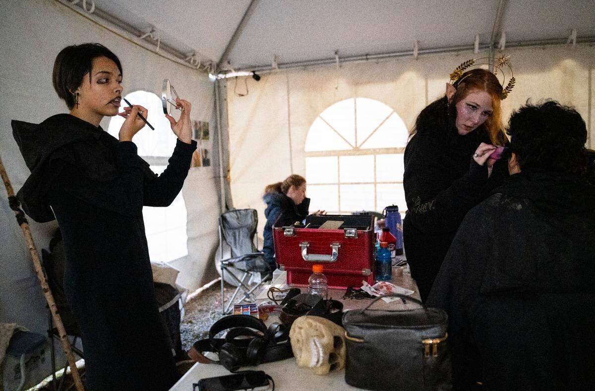 My Haunted Forest actor Adrian Baldwin, left, applies makeup to their face as makeup artist Charlotte Hallowell, right, applies makeup to another actor’s face as they prepare to scare people along the haunted trail at Grand Farms in Vaughn, Wash. on Oct. 23, 2022.
