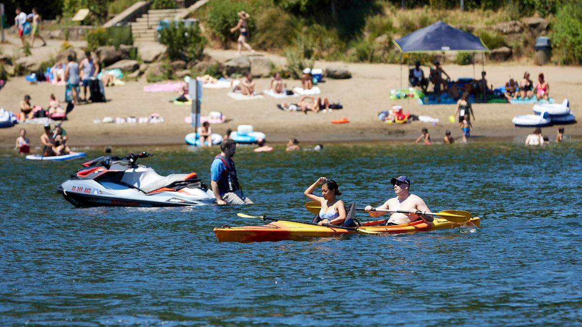 Kayakers paddle in the Willamette River near George Rogers Park to escape from the heat during a record-setting heat wave in Lake Oswego, Oregon, in June. A 22-year-old woman died Wednesday after being pulled underwater by the current while wading in the Willamette River, police say.