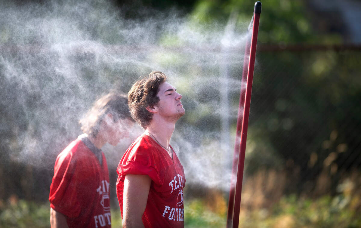 Tenino senior running back Dylan Spicer cools off in the mist during a break at football practice at Tenino Beaver Stadium in Tenino, Washington on Thursday, Aug. 25, 2022.