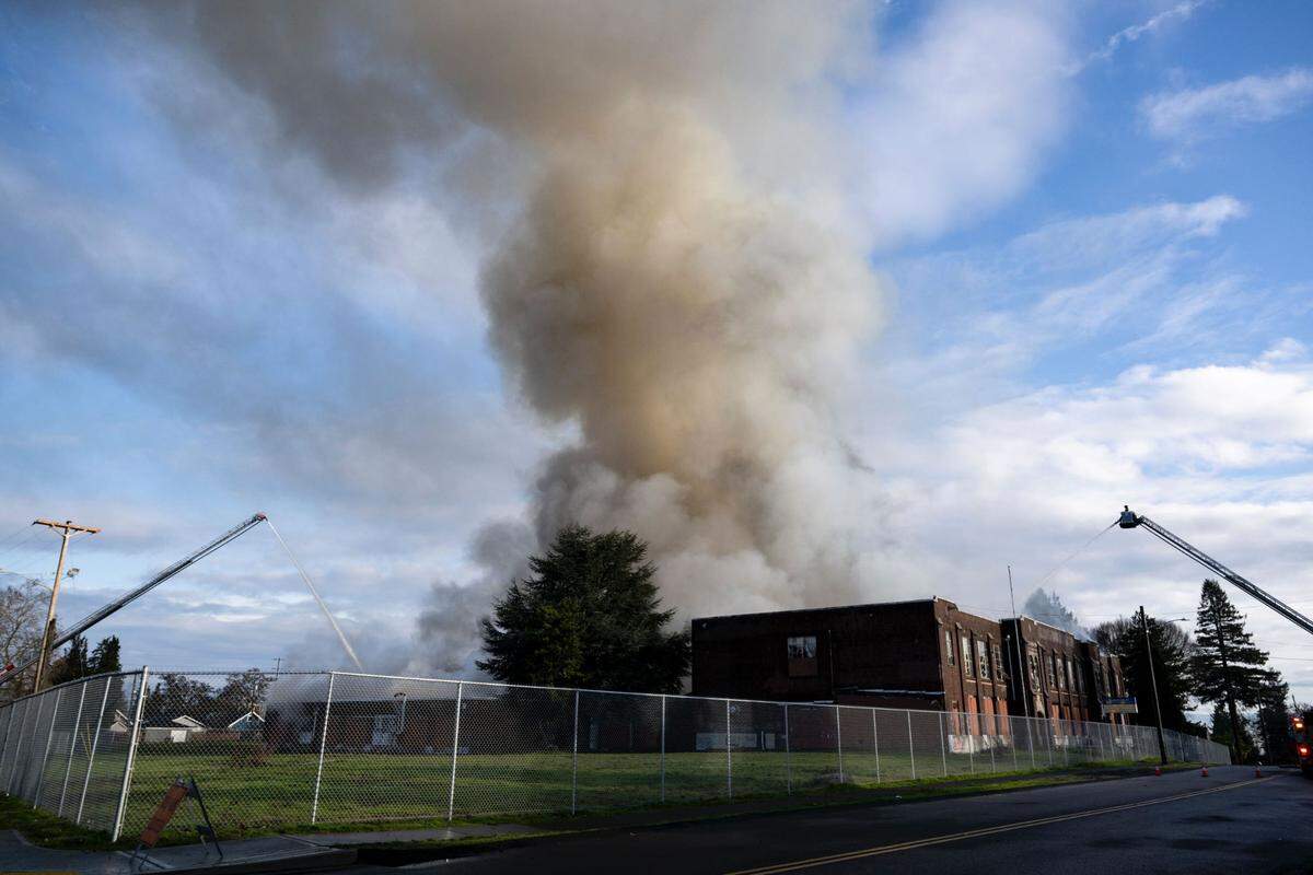 Firefighters spray down the roof of Gualt Middle School in Tacoma, Wash., on Wednesday, Jan. 3, 2024. The abandoned school building caught fire earlier on Wednesday morning.
