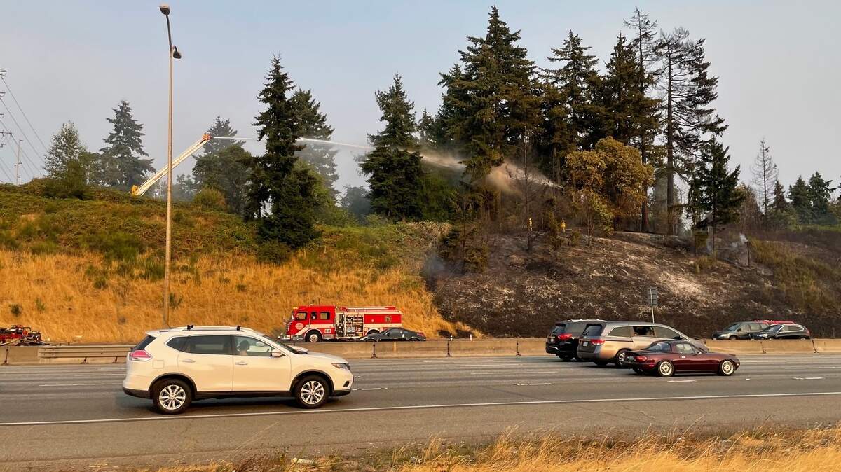 A Tacoma firefighter sprays water to extinguish a fire between Interstate 5 and Wapato Park. The fire burned about an acre of land near I-5 and caused northbound traffic delays.