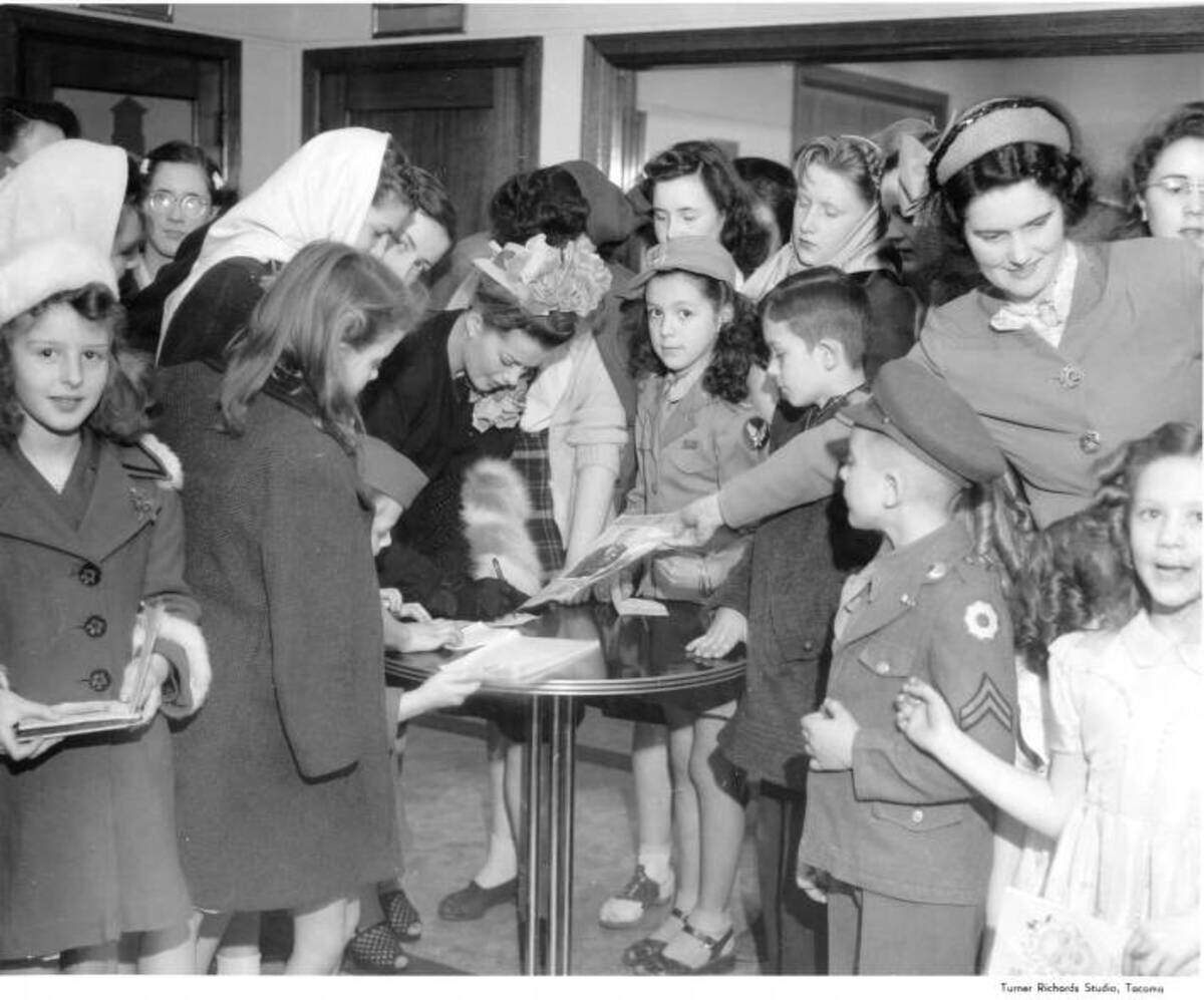 Actress Janis Paige signs autographs for children at KMO Studios in 1946. Children appear to be service dependents.