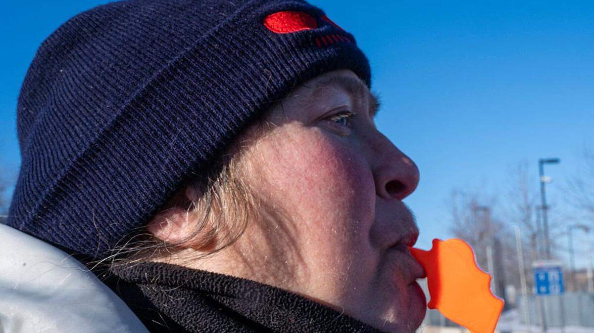 A protester blows into a whistle in the shape of the state of Minnesota near the  entrance to the Bishop Henry Whipple Federal Building in Minneapolis, Minnesota on January 30, 2026. Donald Trump's border chief said January 29, 2026 that some federal agents could be withdrawn from Minneapolis, the northern US city that has become the flashpoint for the president's immigration crackdown. The Trump administration, facing a public backlash over the shooting deaths of two Americans by federal agents in Minneapolis, also eased immigration operations in the northeastern state of Maine. (Photo by ROBERTO SCHMIDT / AFP via Getty Images)