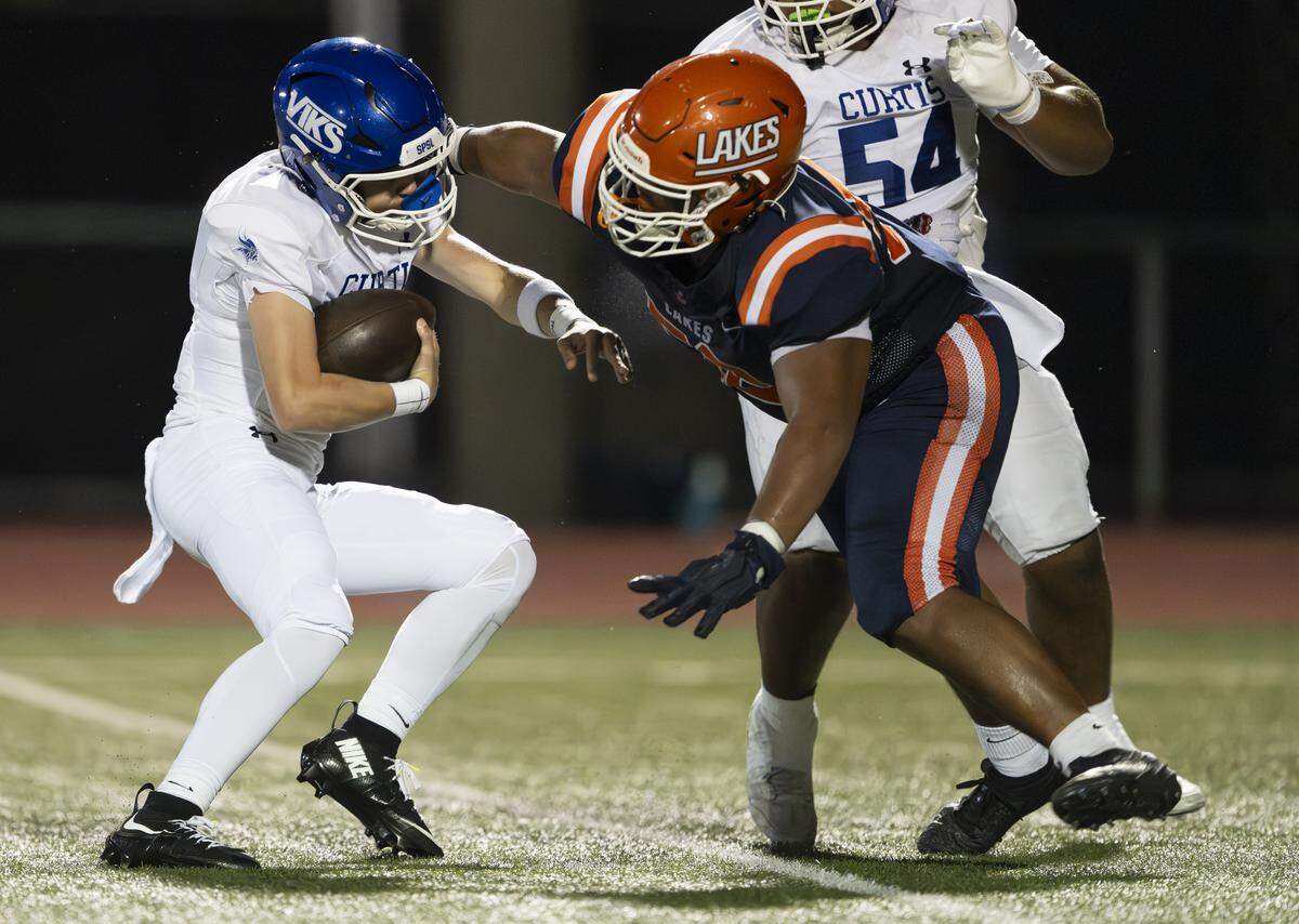 Curtis quarterback Samuel Patterson (2) evades the tackle of Lakes defensive lineman Fili Laulu (54) during the first half of the game at Harry Lang Stadium, on Friday, Sept. 19, 2025, in Lakewood, Wash.