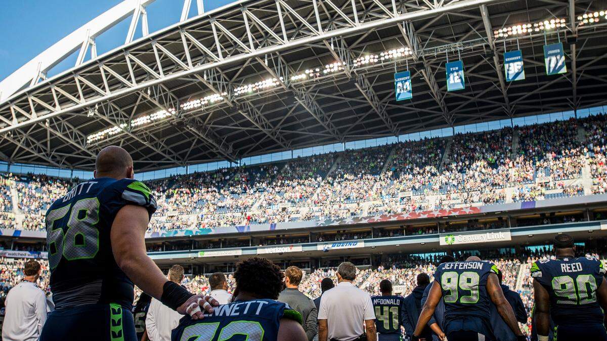Seattle Seahawks offensive lineman Justin Britt stands in support of Seahawks defensive lineman Michael Bennett as he sits for the national anthem in a preseason game at CenturyLink Field last year. Bennett continued the protest throughout the season. He's no longer with the team.