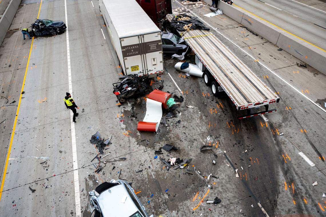Multiple vehicles sit mangled in the northbound lanes of Interstate 5 after a fatal collision just below the 38th Street overpass in Tacoma, Wash., on Friday, March 18, 2022. One person was declared dead at the scene after the wreck, while the driver of the maroon flatbed semi-truck was determined to be the cause of the accident, according to investigators from the Washington State Patrol. It was also noted that the driver of the truck was taken into custody from driving under the influence.