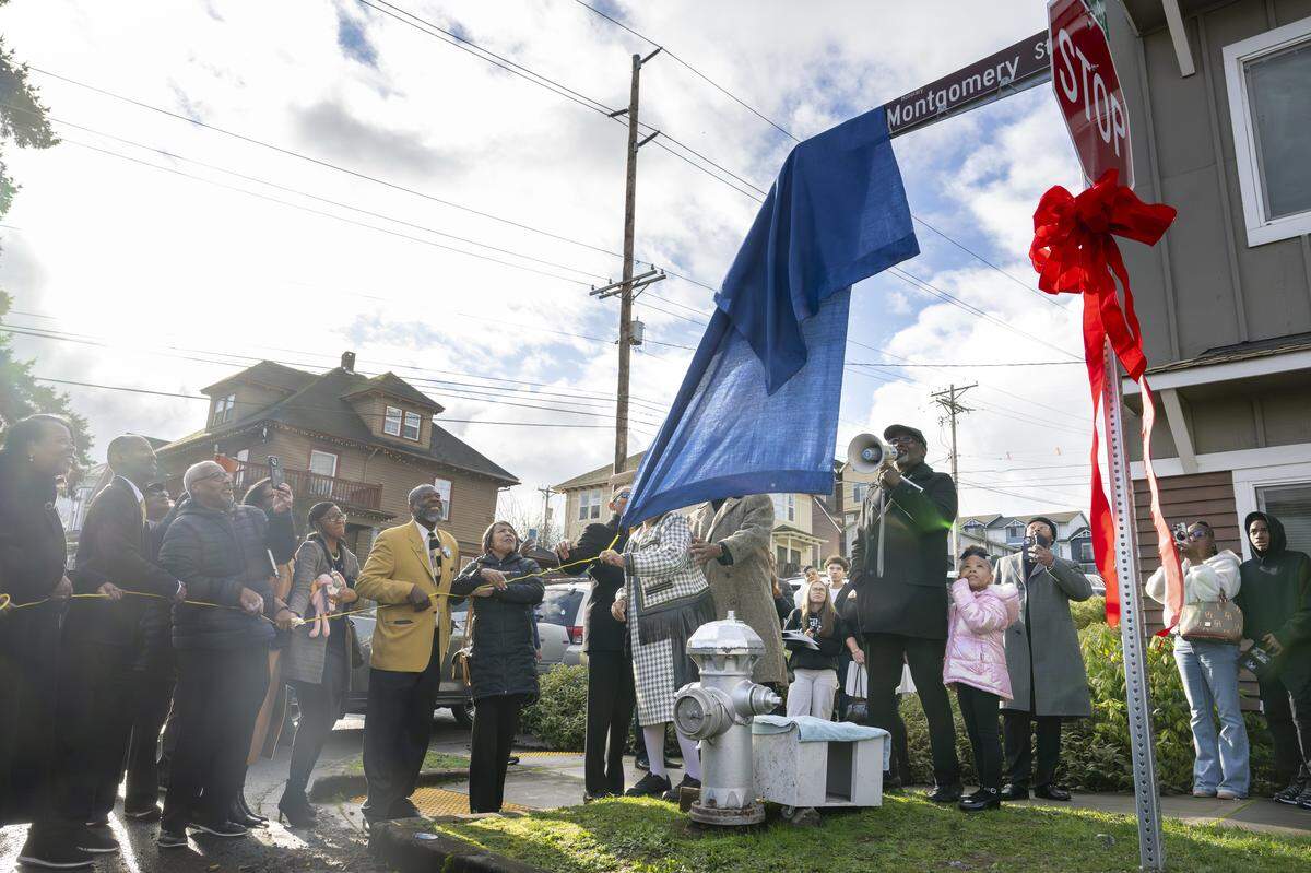 The children of Bishop Curtis E. Montgomery, along with Mayor Victoria Woodards, reveal the honorary Curtis E. Montgomery Street sign on Saturday, Dec. 27, 2025, at the intersection of G and South 21st streets in Tacoma, Wash.