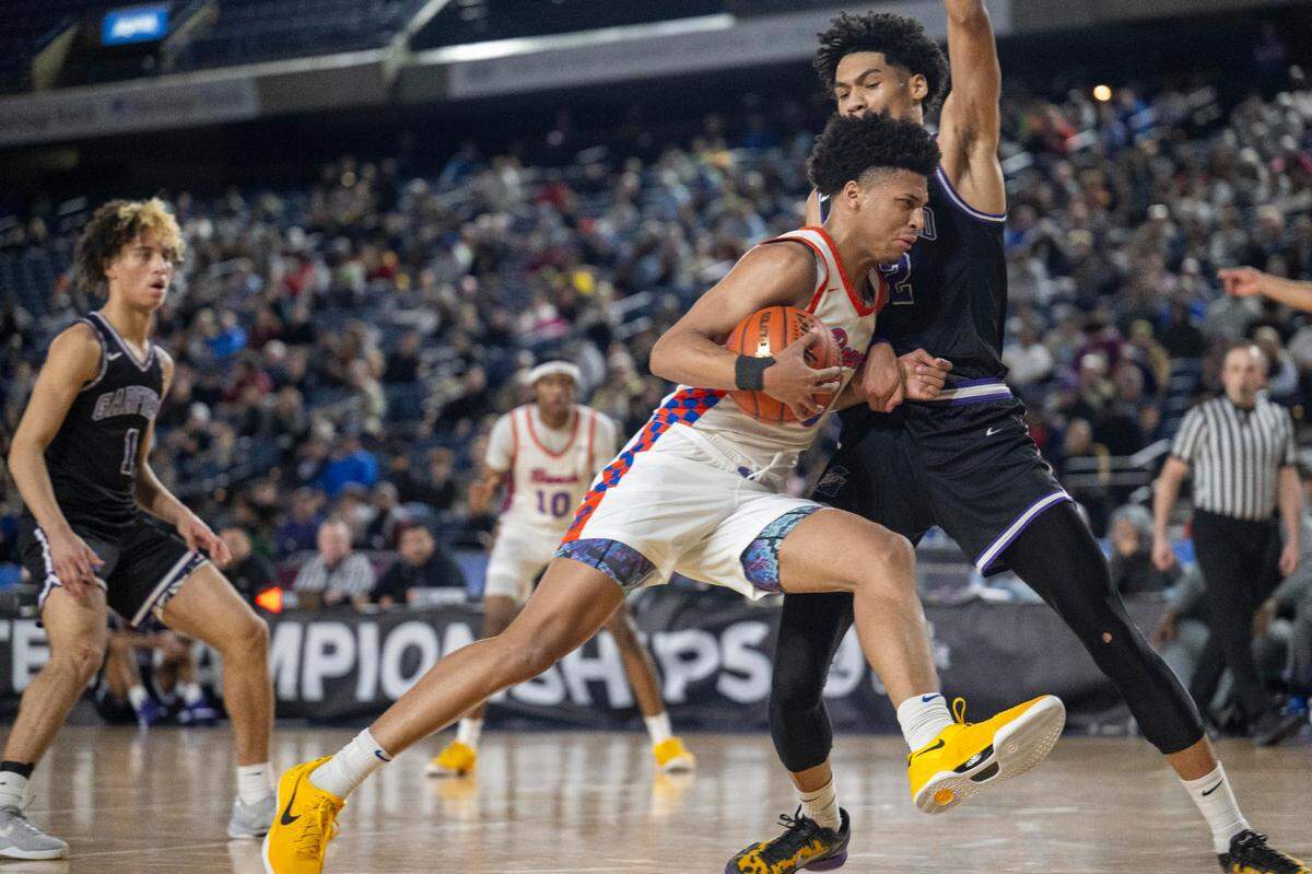 Rainier Beach guard Kaden Powers (0) drives to the basket as Garfield forward JuJu Ervin (22) defends during the fourth quarter of a Class 3A state basketball tournament semifinal game at the Tacoma Dome on Friday, March 7, 2025, in Tacoma, Wash.