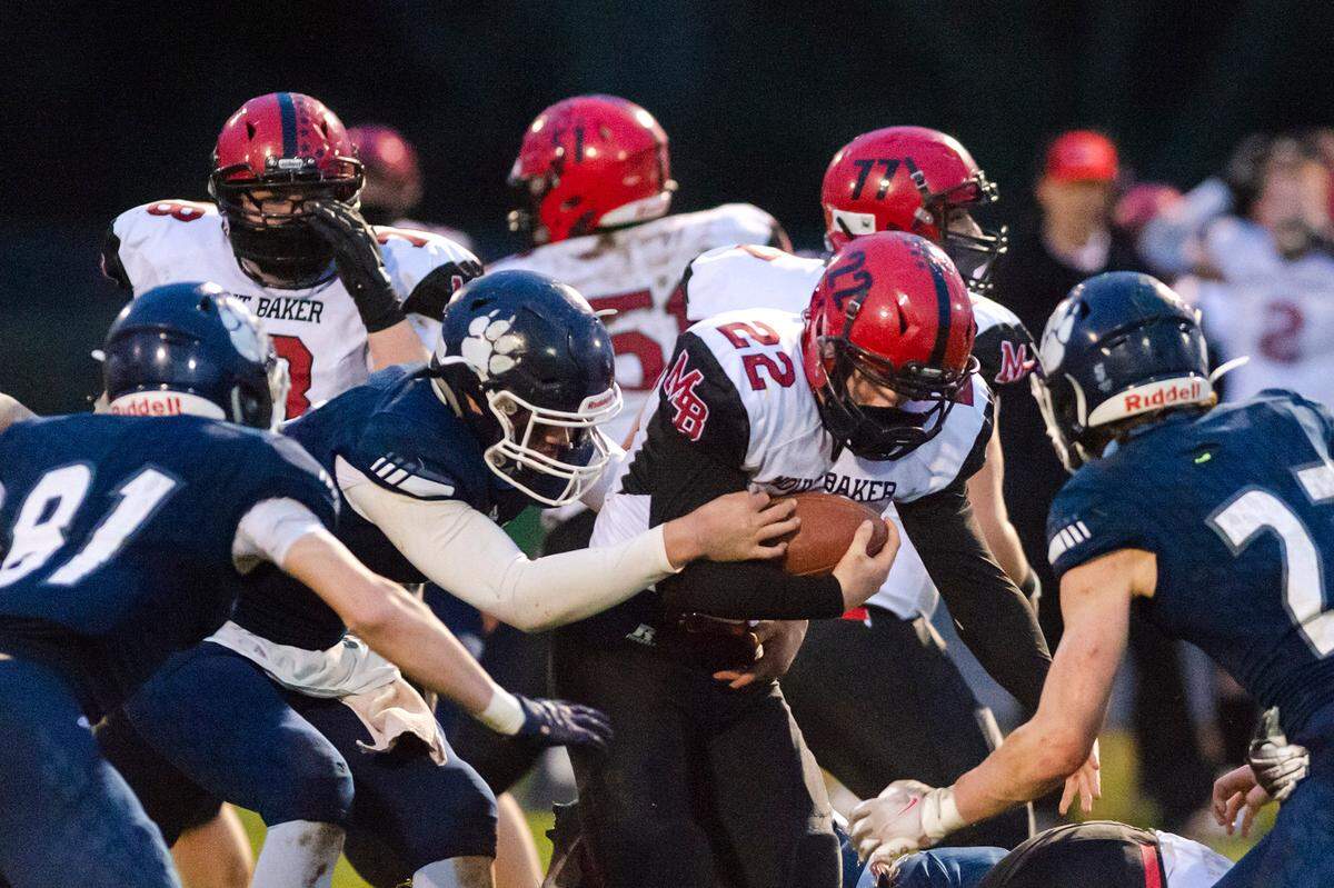 Mount Baker running back Jesse Sande (22) is surrounded and stopped by Lynden Christian defenders at the line of scrimmage during the 2nd quarter on Saturday evening March 20, at Lynden Christian. Lynden Christian defeated Mount Baker 33 to 14.