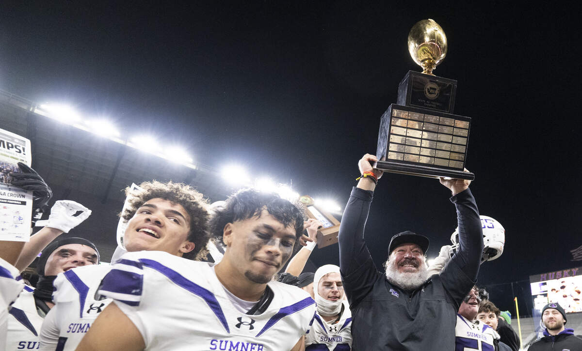 Sumner Spartans head coach Keith Ross hoist the trophy  after Sumner’s 41-25 victory against Lake Stevens in the 4A State Championship game at Husky Stadium, on Saturday, Dec. 6, 2025, in Seattle.
