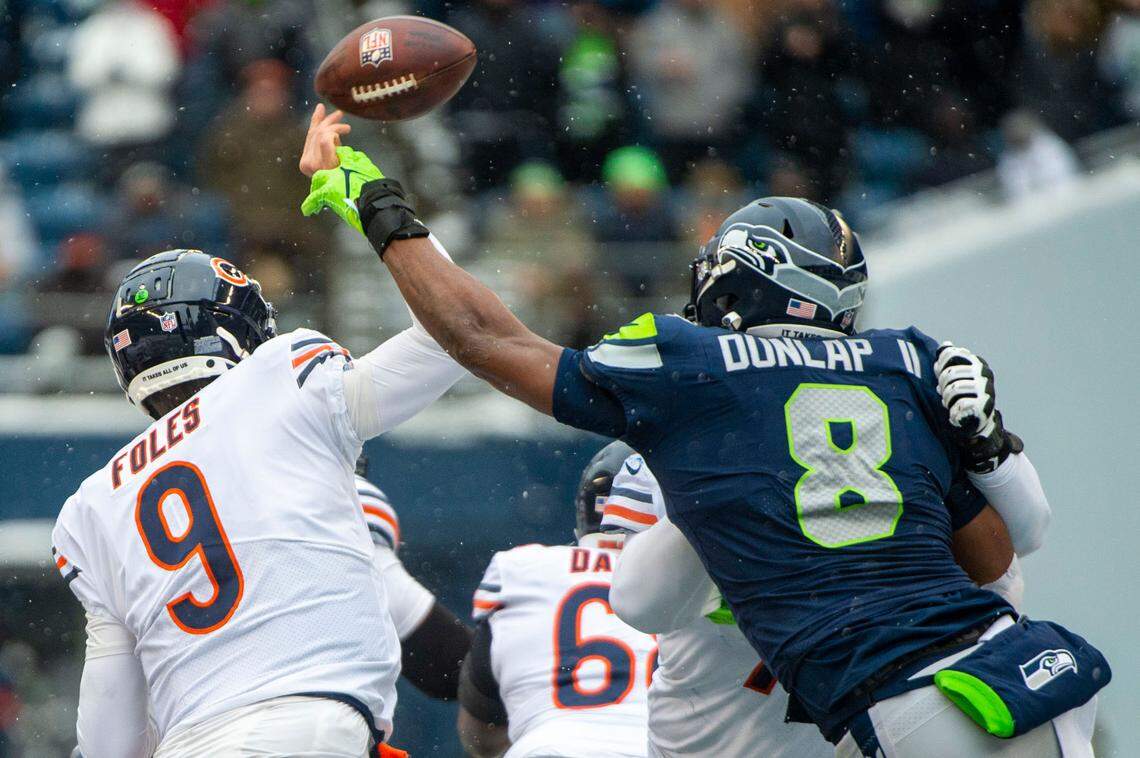 Seattle Seahawks defensive end Carlos Dunlap (8) knocks the ball out of the hand of Chicago Bears quarterback Nick Foles (9) during the second quarter of an NFL game on Sunday afternoon at Lumen Field in Seattle. Initially it was called a fumble, but the play was overturned and called an incomplete pass.