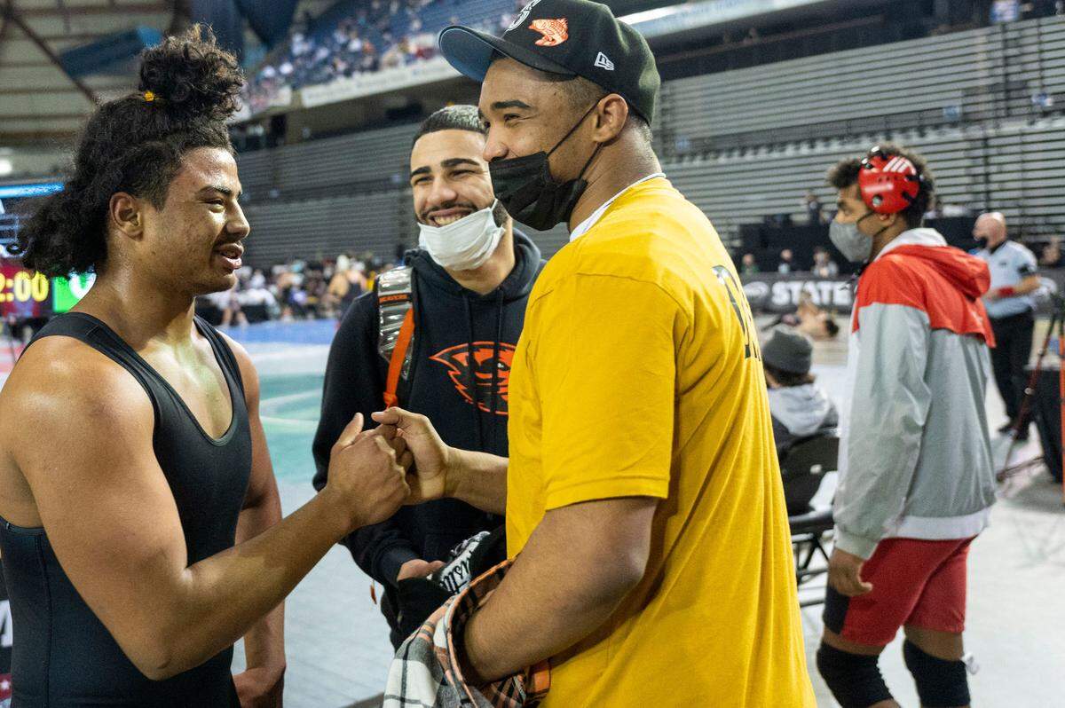 Lincoln’s Navarre Dixon (left) shakes hands with his brother, J.J. Dixon — a former Lincoln state-champion wrestler, after Navarre’s pin of Cheney’s Ezra Anderson in a 182-pound 3A quarterfinal match at Mat Classic XXXIII on Friday, Feb. 18, 2022, in Tacoma, Wash.