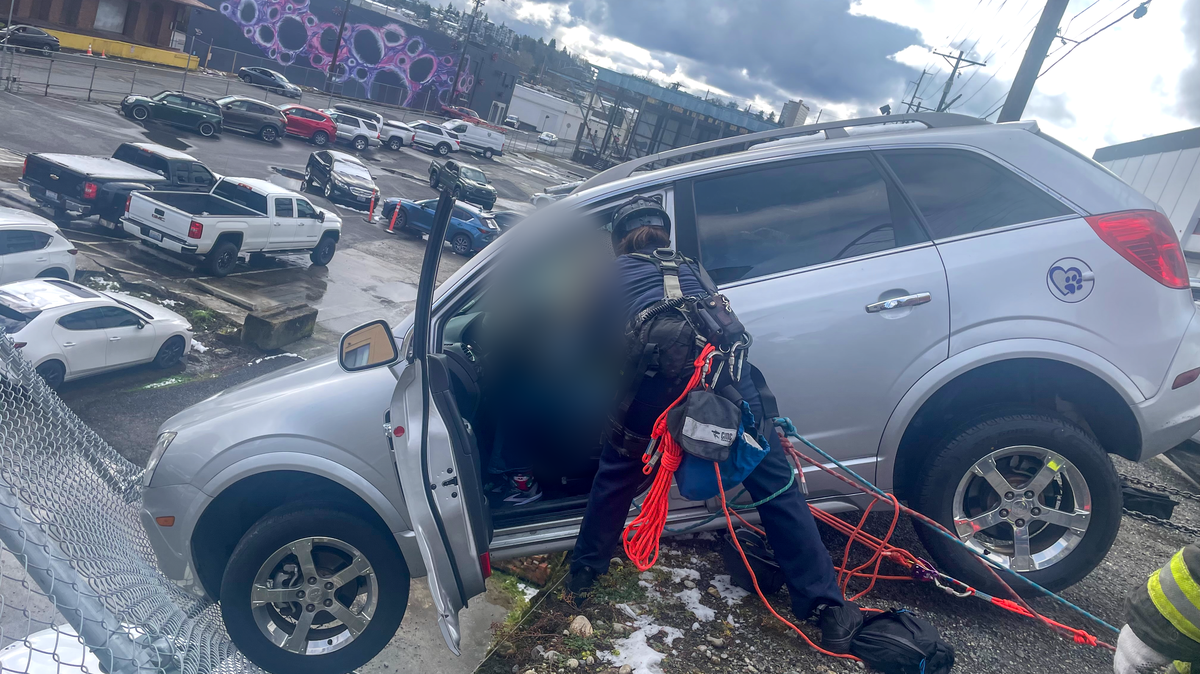 A member of the Tacoma Fire Department technical rescue team removes the driver of a car dangling off a 20-foot drop into a downtown parking lot on Saturday, March 14, 2026.