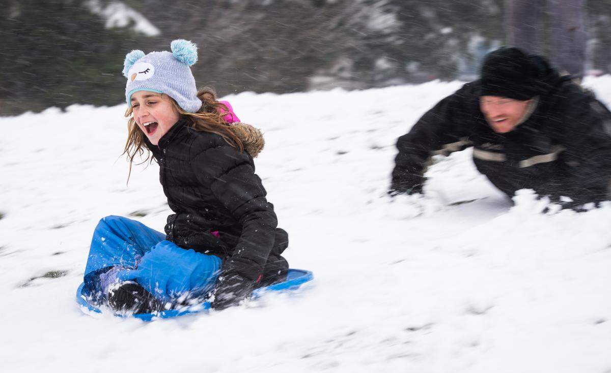 Lucy McElligott gets a push from her dad Patrick as she speeds down a hill at Vassault Park in Tacoma, Wash., on Friday, Feb. 8, 2019.