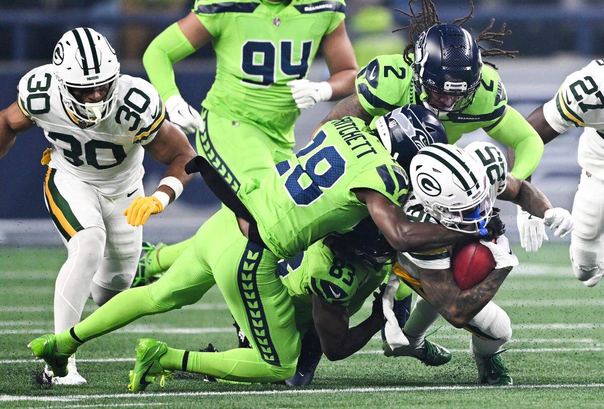Green Bay Packers cornerback Keisean Nixon (25) is tackled on the kick return by Seattle Seahawks cornerback Nehemiah Pritchett (28) and safety Rayshawn Jenkins (2) during the first quarter of the game at Lumen Field, on Sunday, Dec. 15, 2024, in Seattle, Wash.