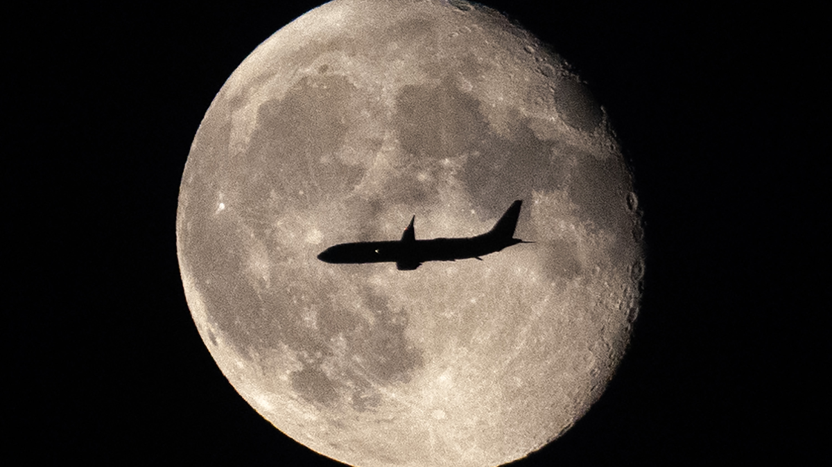 A plane flies in front of the super blue moon above Seattle-Tacoma on Aug. 30, 2023.
