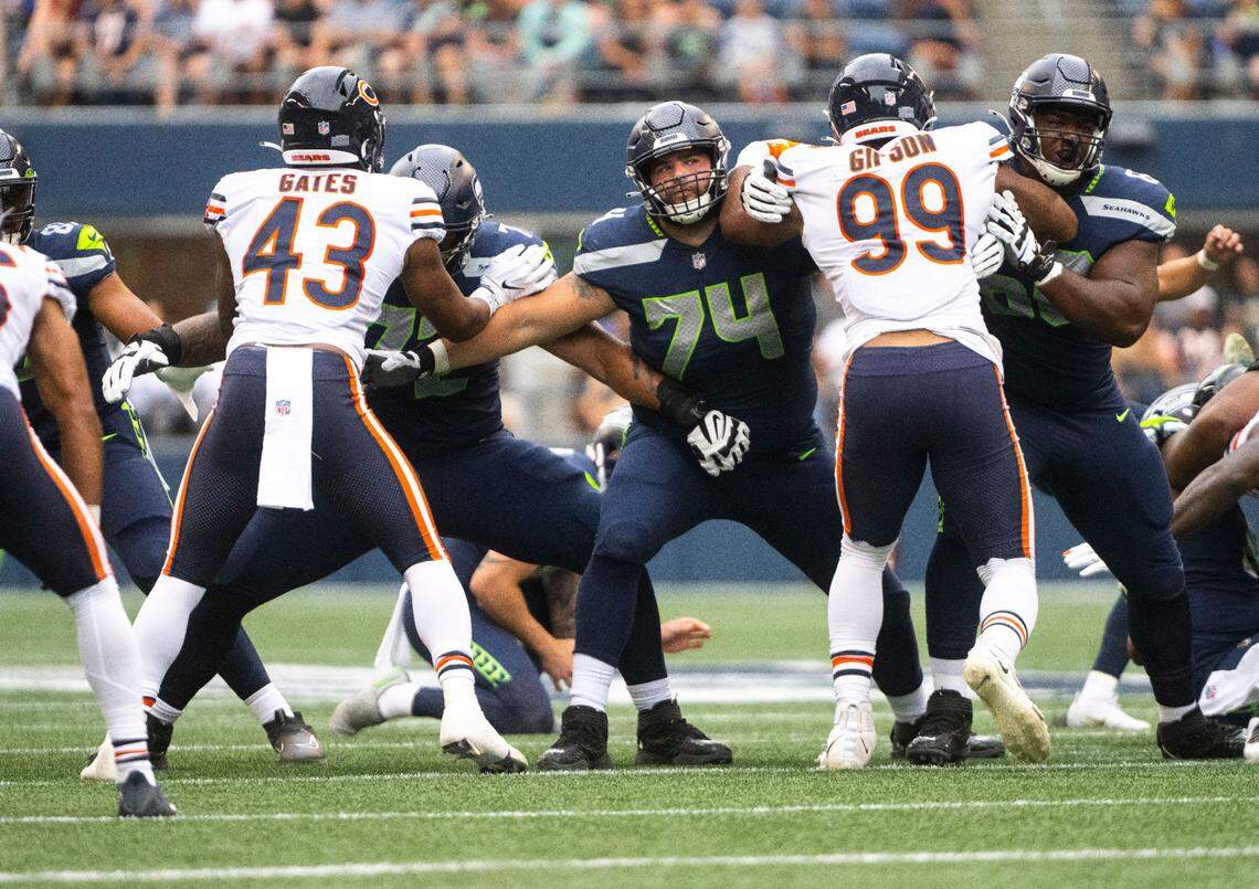 Seattle Seahawks offensive tackle Jake Curhan (74) tries to hold back Chicago Bears linebacker deMarquis Gates (43) and Chicago Bears defensive end Trevis Gipson (99) during the first half of the Seahawks second preseason game at Lumen Field in Seattle, Wash. on August 18, 2022.
