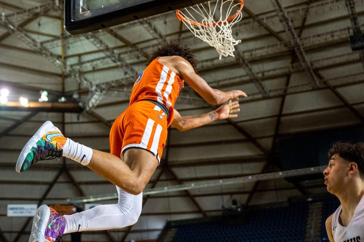 Graham-Kapowsin’s Joshua Wood (3) releases the rim after dunking the ball on a fastbreak during the second quarter of a Class 4A state tournament game against Davis on Wednesday, March 2, 2022, at the Tacoma Dome, in Tacoma, Wash.