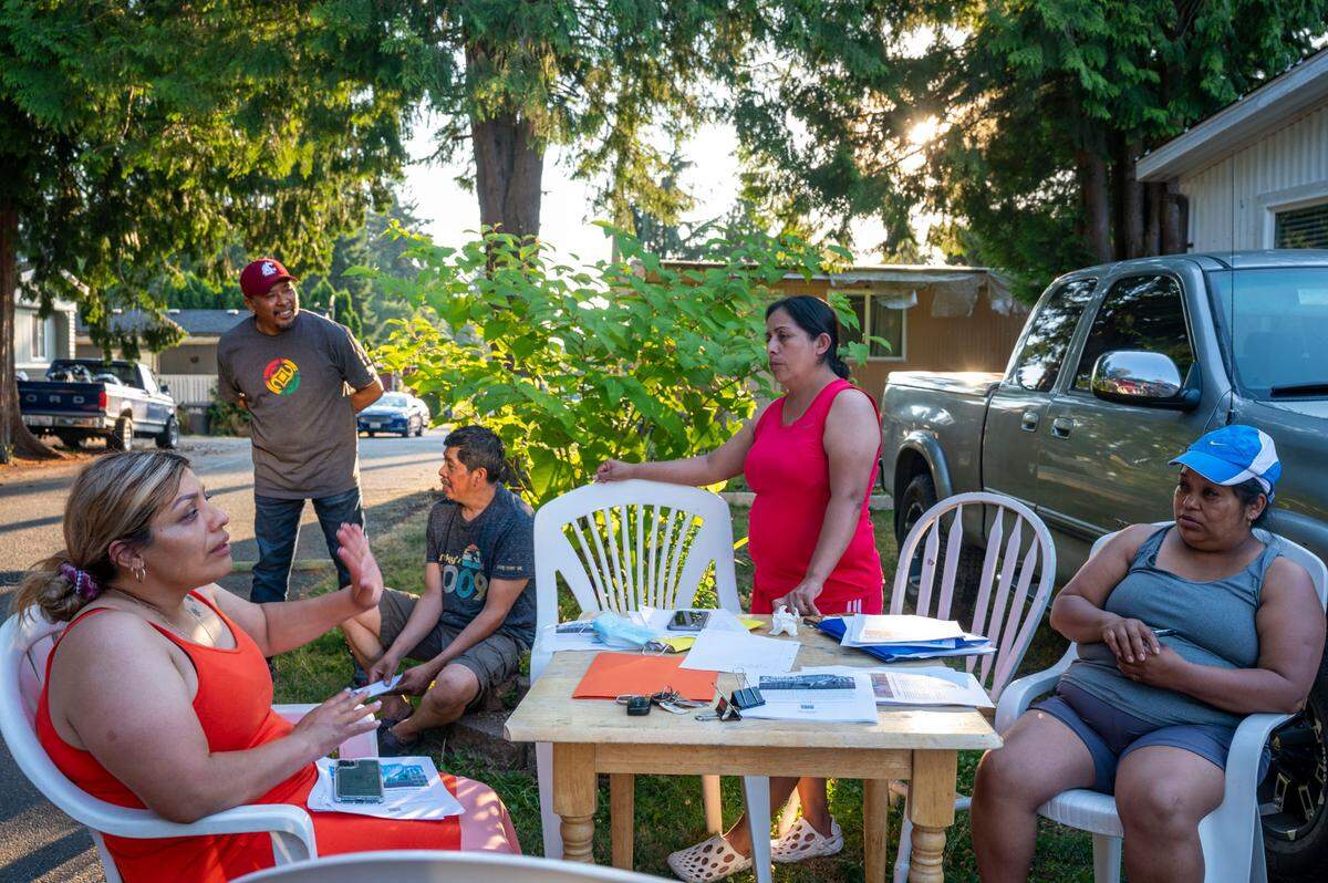 Residents of Meridian Estates gather outside the home of Saraim Nieto (right) as they listen to a group of housing advocates talk to them about actions they might be able to take to get more money for their homes from the developer of the property on Thursday, July 28, 2022. In December 2021, Timberlane Partners bought the property where Meridian Estates is located. The developers plan to build an apartment complex where the mobile home park now stands. All of the Meridian Estates residents were given notice to leave by October 2022.