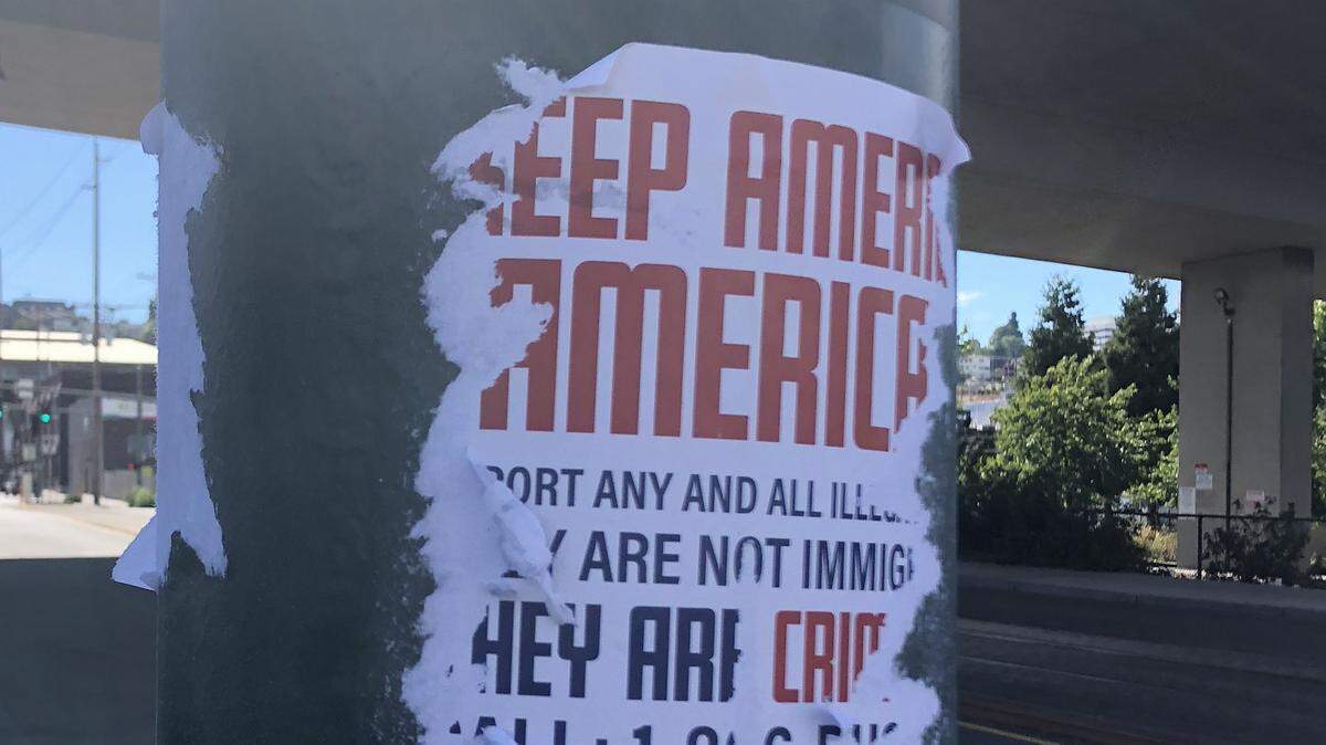 A poster produced by a white supremacist group is glued to a Tacoma city utility pole at South 25th and A Streets Sunday. It had already been partially torn down before being scrubbed off by Halley Knigge.