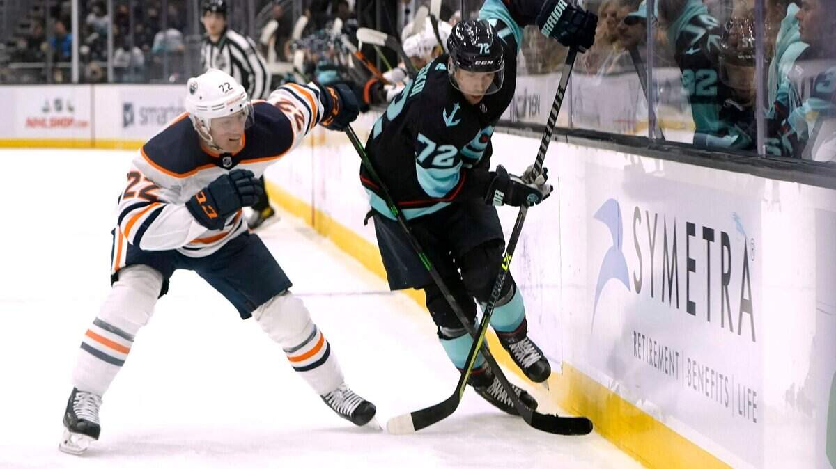 Edmonton Oilers defenseman Tyson Barrie (22) reaches across Seattle Kraken right wing Joonas Donskoi toward the puck during the first period of an NHL hockey game Friday, Dec. 3, 2021, in Seattle. (AP Photo/Elaine Thompson)