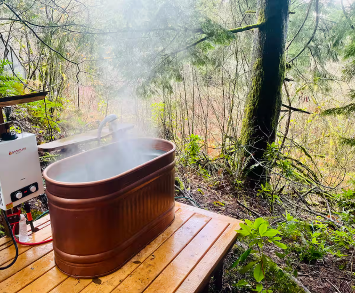 The treehouse Airbnb hosted by Erica and Tim features this photo of the tub setup, captioned “Soaking tub filled with either hot or cold water. A propane fueled on-demand water unit fills the tub to the temp of your liking.”