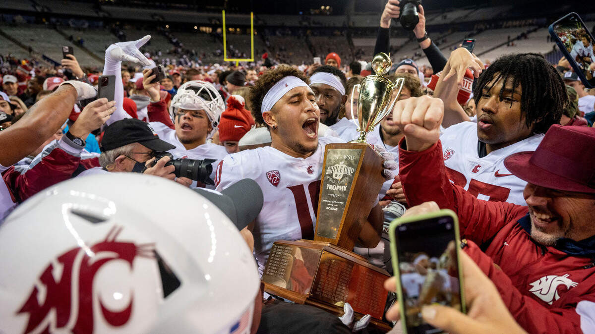 Washington State defensive end Ron Stone Jr. (10) celebrates while holding the Apple Cup trophy after the Cougars beat Washington 40-13 in a Pac-12 game on Friday evening at Husky Stadium in Seattle.