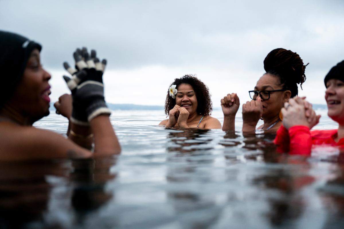 Tiffanie Majors, center, submerges in the frigid waters of the Puget Sound at Sunnyside Beach, on Sunday, Jan. 12, 2025, in Steilacoom, Wash.