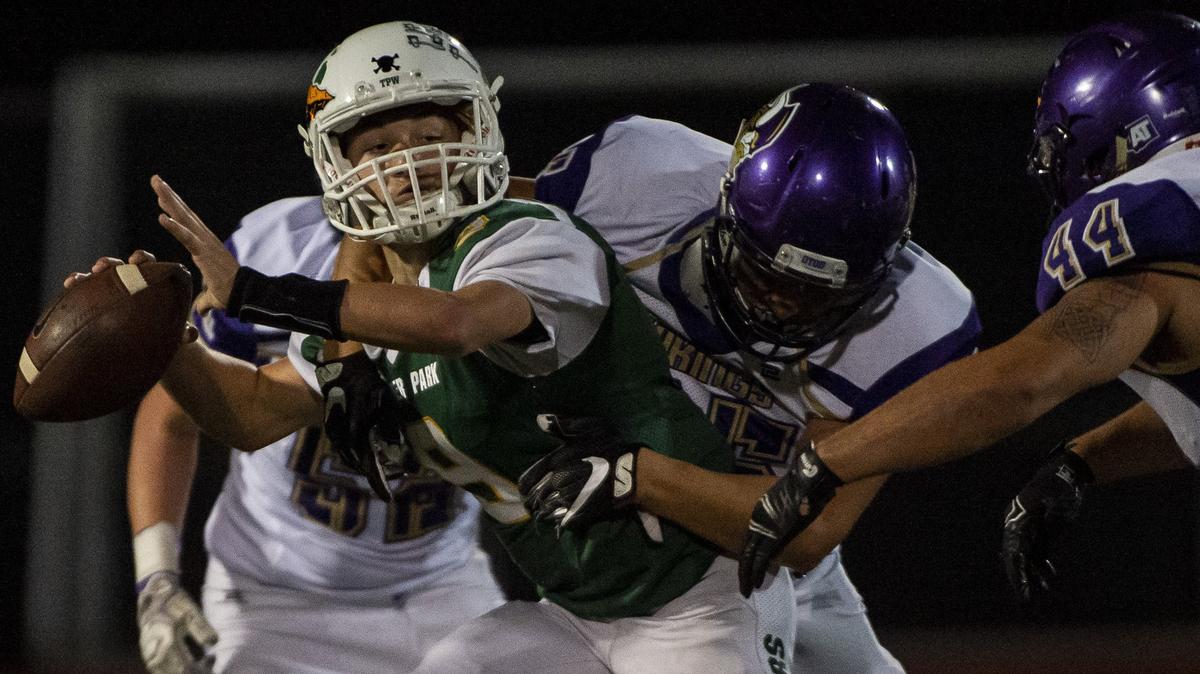 Clover Park’s Noah Yarrington (9) tries to pass while hit by North Kitsap’s Cameron Pelegri (65) in the second quarter. Clover Park High School played North Kitsap in a football game at Clover Park High School in Lakewood, Wash., on Friday, Sept. 28, 2018.