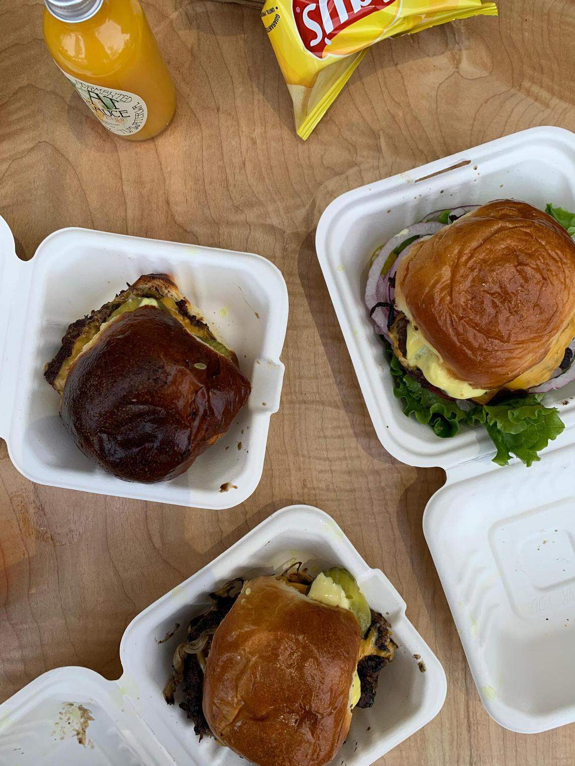 The burgers from Carbon Pop, a South Sound pop-up pictured here at Top Rung Brewing in Lacey, Wash., with the LTO version on the right and one with onions frizzled into the patio on the left.
