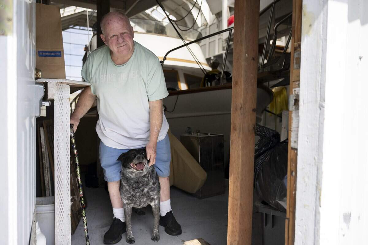 Toni Froehling stands with his dog, Weasel, at his boat house stationed at Breakwater Marina on Tuesday, May 12, 2026, in Tacoma, Wash.