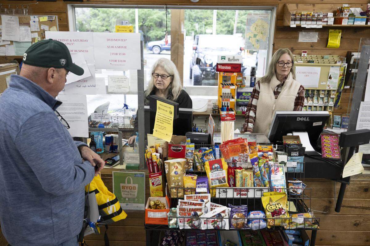 Anderson Island General Store owner Barbara Lake, center, and Toria Estes, right, a volunteer helper, ring up customer purchases on the last day of business for the store on Monday, Feb. 2, 2026, in Anderson Island, Wash. Lake, a 33-year resident on the island, made the decision to close the store after running it for 17 years.