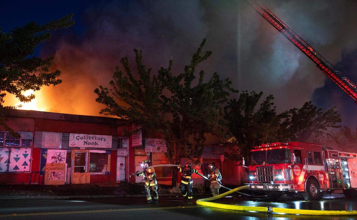 Firefighters prepare to add more water to the business fire on I Street in the Stadium District of Tacoma, Washington, on Thursday, Aug. 3, 2023.