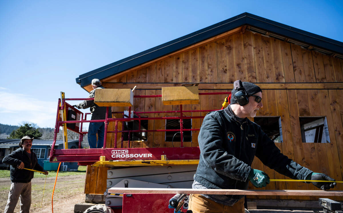 McMillin Farm employee Mark Bridges, right, measures a board as Greg Bridges, center, and Jesus Padilla, left, work on building a store that will be used to sell produce that’s grown on the farm near Puyallup, Wash. on Saturday, March 12, 2022.