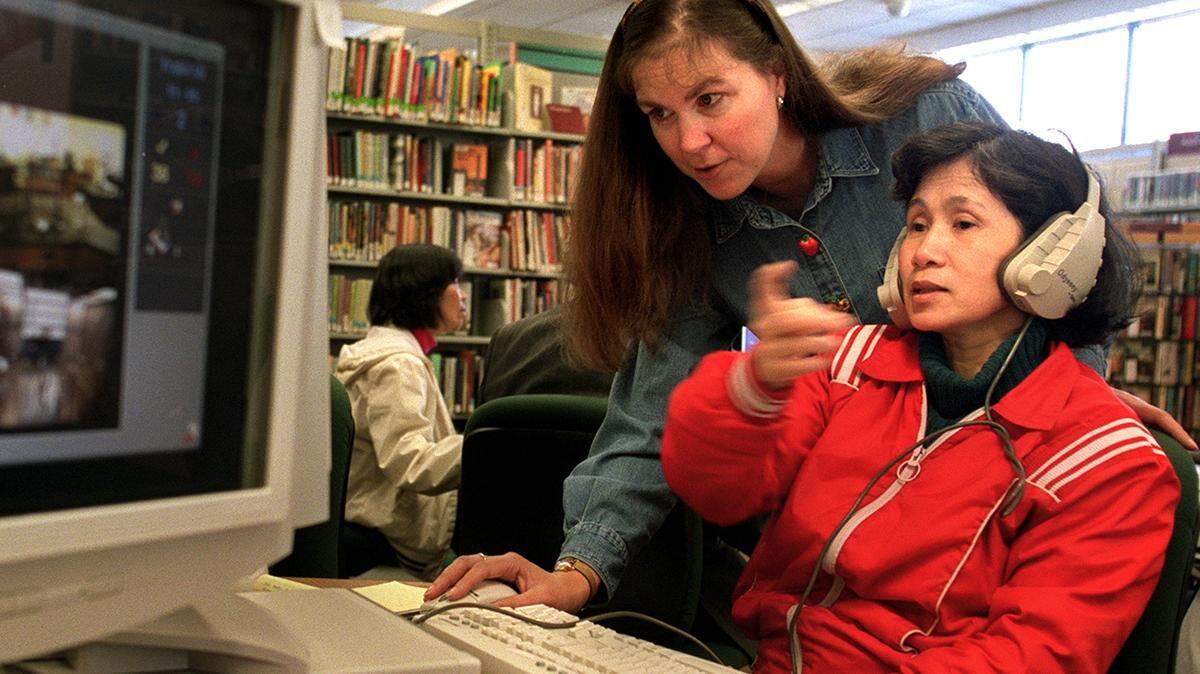 Hiep Nguyen, right, works on an English language commuter program while getting assistance from Teresa Noll an English as a Second Language teacher at the Swan Creek Library on Tuesday, October 1, 2002. The Swan Creek Library closed in 2011. (Janet Jensen/The News Tribune)