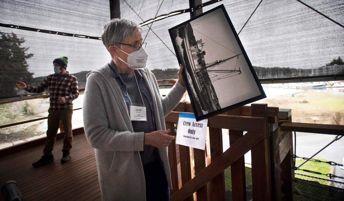 Janet Stahnke, a docent at the Harbor History Museum, holds a historic photo of the 65-foot Shenandoah fishing vessel, currently under restoration at the museum in Gig Harbor, Washington, on Thursday, Feb. 3, 2022.