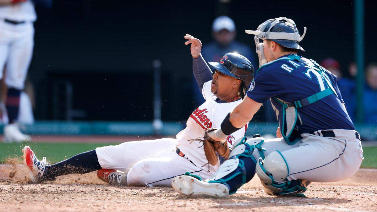 Cleveland Guardians’ Jose Ramirez, left, scores the game winning run past Seattle Mariners catcher Cal Raleigh on a fielders choice by Josh Bell during the 12th inning of a baseball game, Sunday, April 9, 2023, in Cleveland. (AP Photo/Ron Schwane)