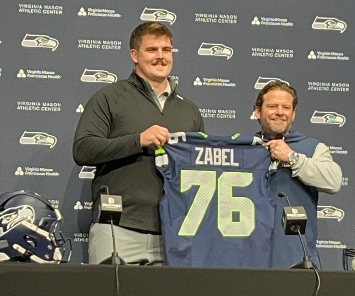 Grey Zabel (76) holds his new jersey with general manager John Schneider five days after the Seahawks made the first-round choice their highest-drafted interior offensive lineman since 2001 and Steve Hutchinson, at the Virginia Mason Athletic Center in Renton May 1, 2025.