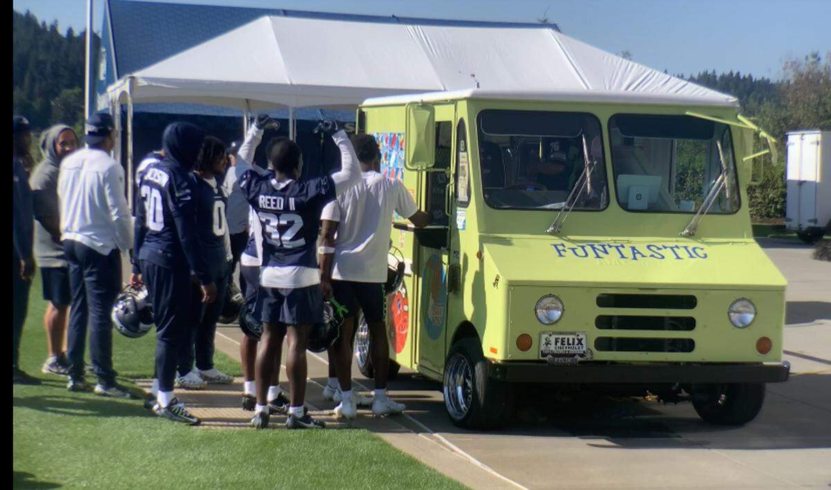Rookie safety Jerrick Reed raises and pumps his arms giddily while waiting with teammates in line at the ice cream truck Pete Carroll had come to Seahawks practice Sept. 21, 2023, three days before they were to play the Carolina Panthers.