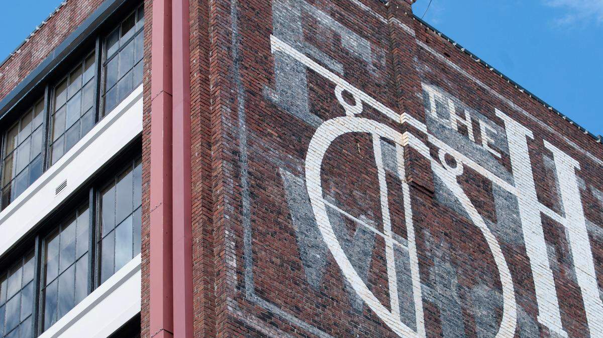 Bright white paint of “The Harmon” covers past F.S. Harmon ghost signs at 1944 Pacific Ave. in Tacoma on July 12, 2023.