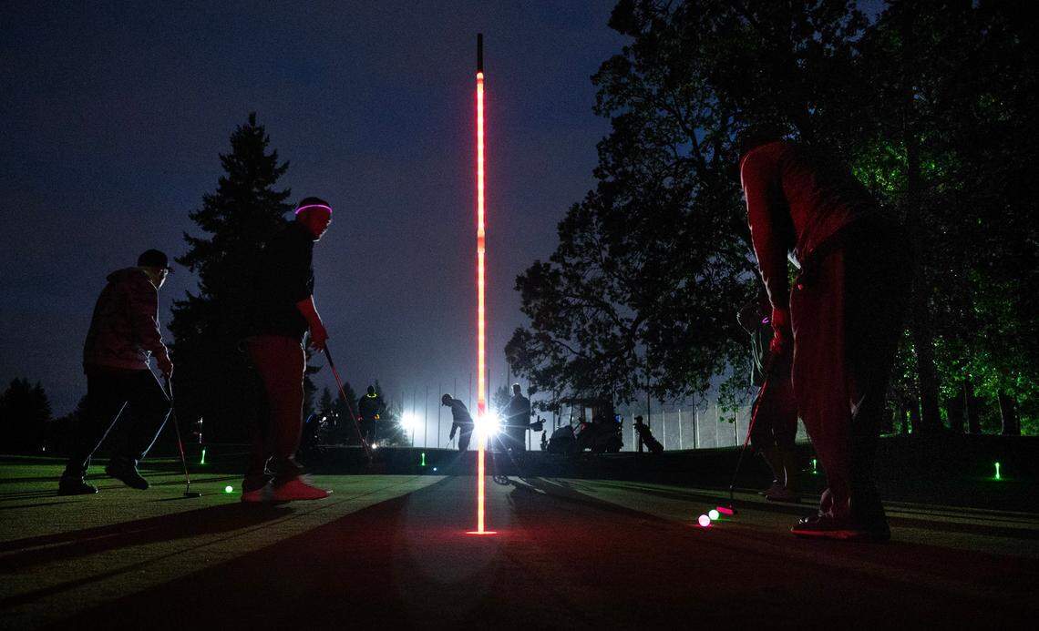 Golfers putt during a Glow Golf nighttime play preview session on the Williams Nine course at Meadow Park Golf Course in Tacoma, Washington, on Tuesday, Sept. 19, 2023.
