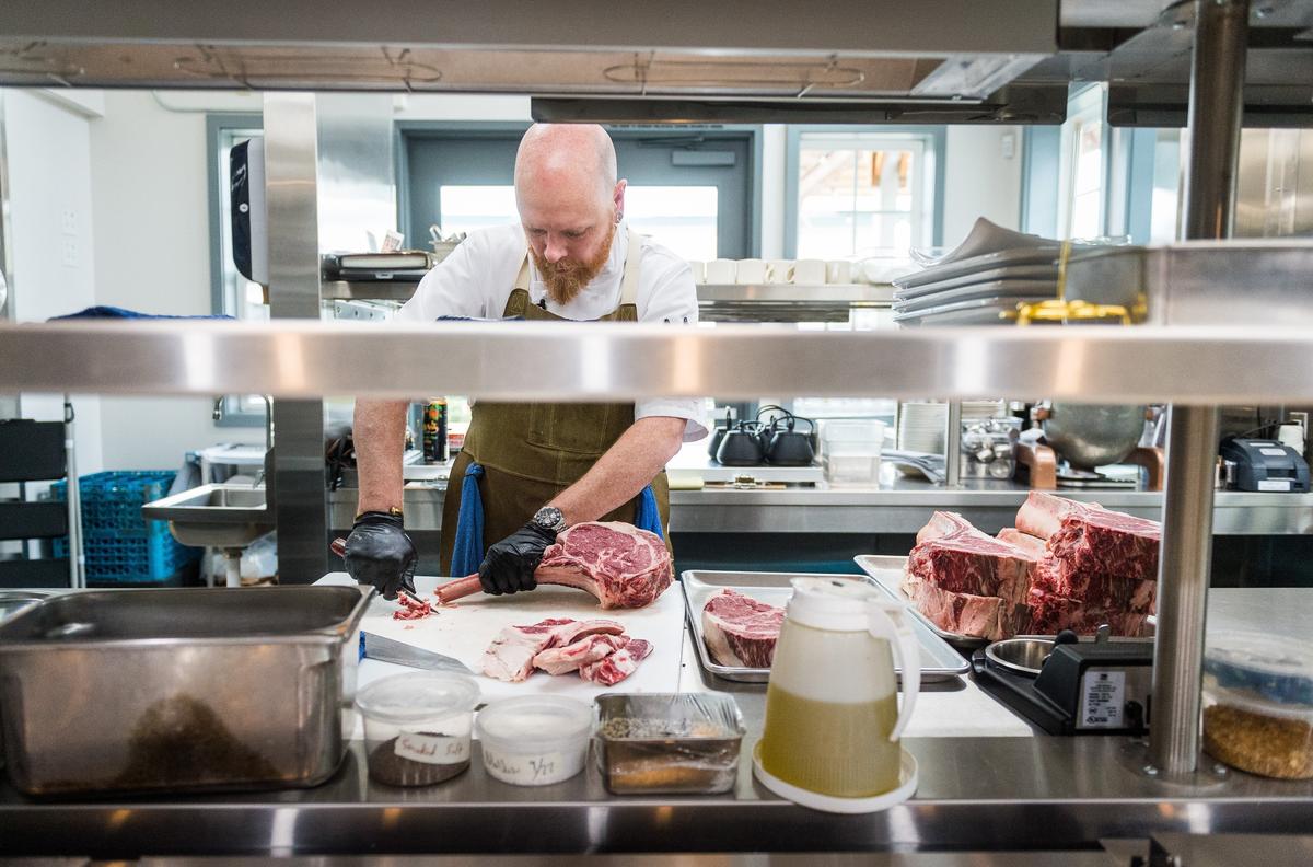 Chef-owner Thad Lyman prepares the dry-aged tomahawk bone-in rib eye steak at Brix 25 in Gig Harbor.