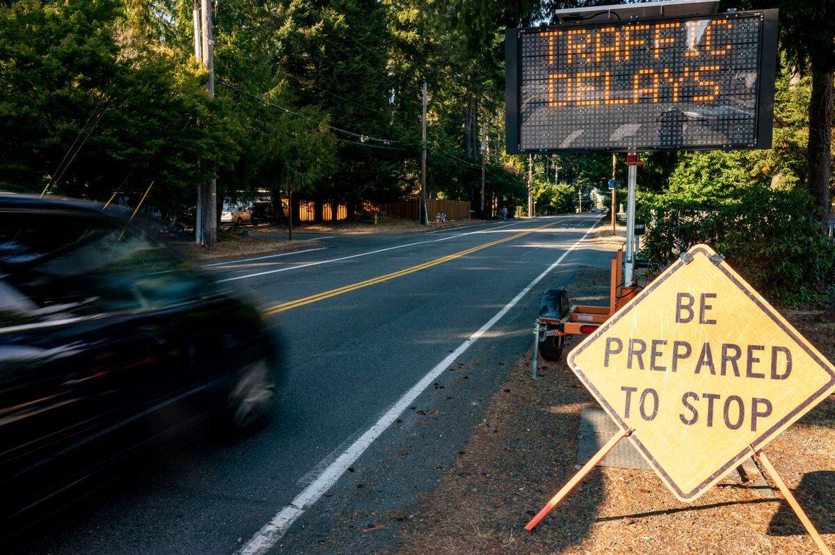 A vehicle drives north on 38th Avenue near 56th Street in Gig Harbor, Wash., past a sign that advises drivers that construction will be occurring along the road on Tuesday, Oct. 4, 2022.
