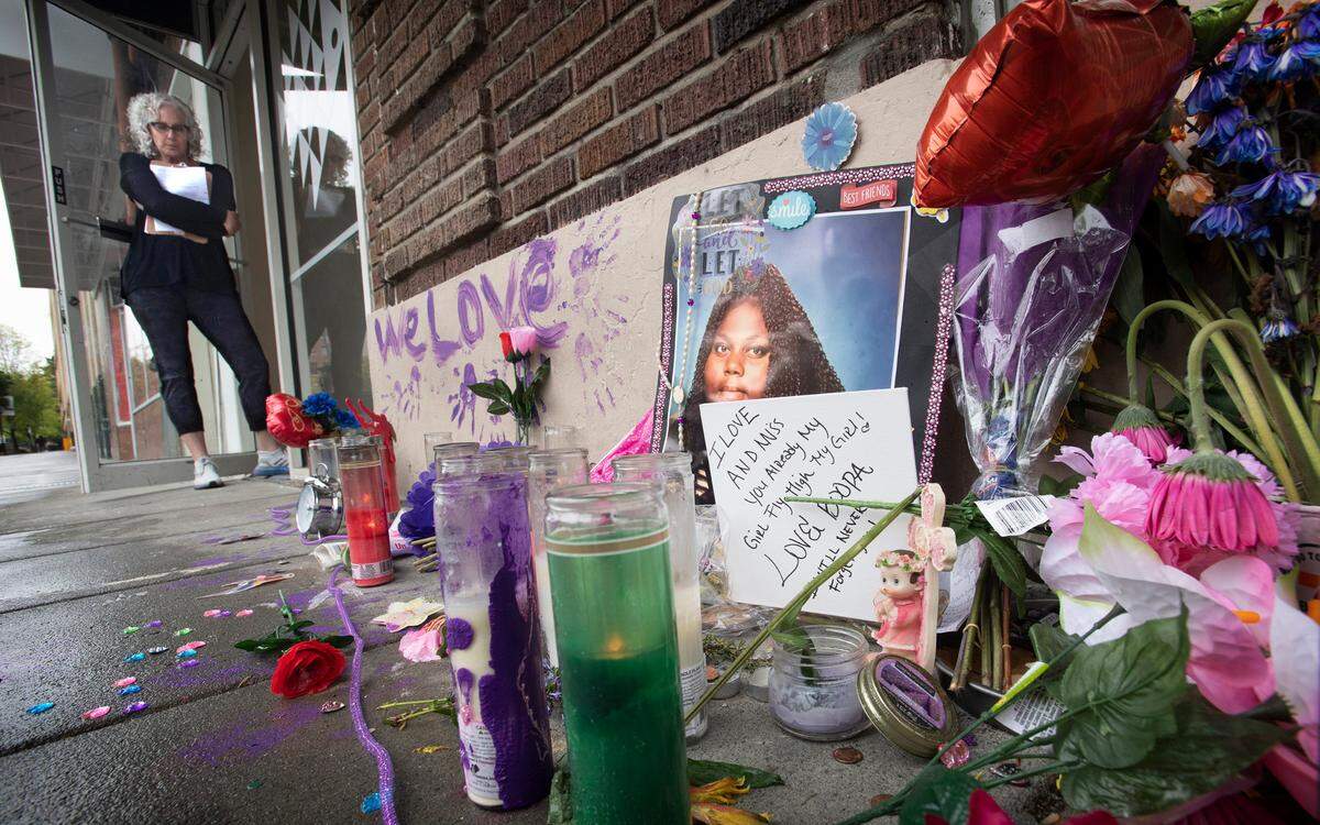 Business owner Jill Fish stands at her doorway on Thursday, May 5, 2022, next to the memorial to Odessa Easterlin, a homeless woman who was fatally stabbed April 30 on Market Street in downtown Tacoma, Washington. “She was a very very giving generous person even though she didn’t have much. She was not a thief,” Fish said after news reports that Easterlin was killed by a store clerk allegeding she was shoplifting. “I loved her,” Fish said of the 37-year-old woman who slept outside her doorway for the past three years. “Everyone is devastated.”