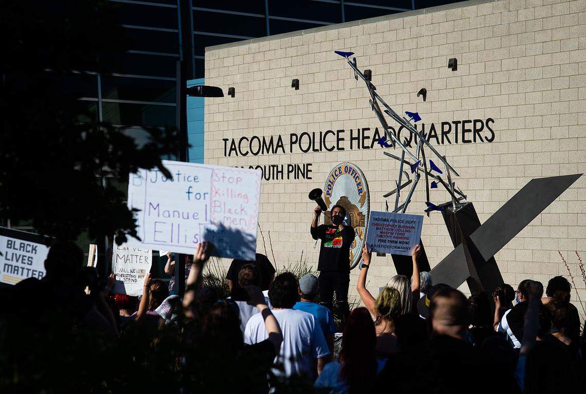 A crowd calls out as local attorney Corddaryl Woodford leads a chant of “Black Lives Matter” outside Tacoma Police Headquarters on South Pine street on June 18, 2020. Protesters gathered and called for action against the police officers involved in the killing of Manuel Ellis in Tacoma.