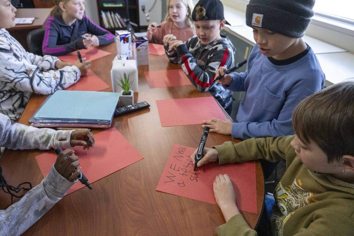 A group of Orting Elementary School fifth graders, including Aleks Obshtyr, left, and Malaki Olmsted, right. work on letters and signs in support of the Orting School District's $137 million bond on Wednesday, Oct. 15, 2025, in Orting, Wash. The group traveled to the Orting Senior Center to share these with residents the next day.