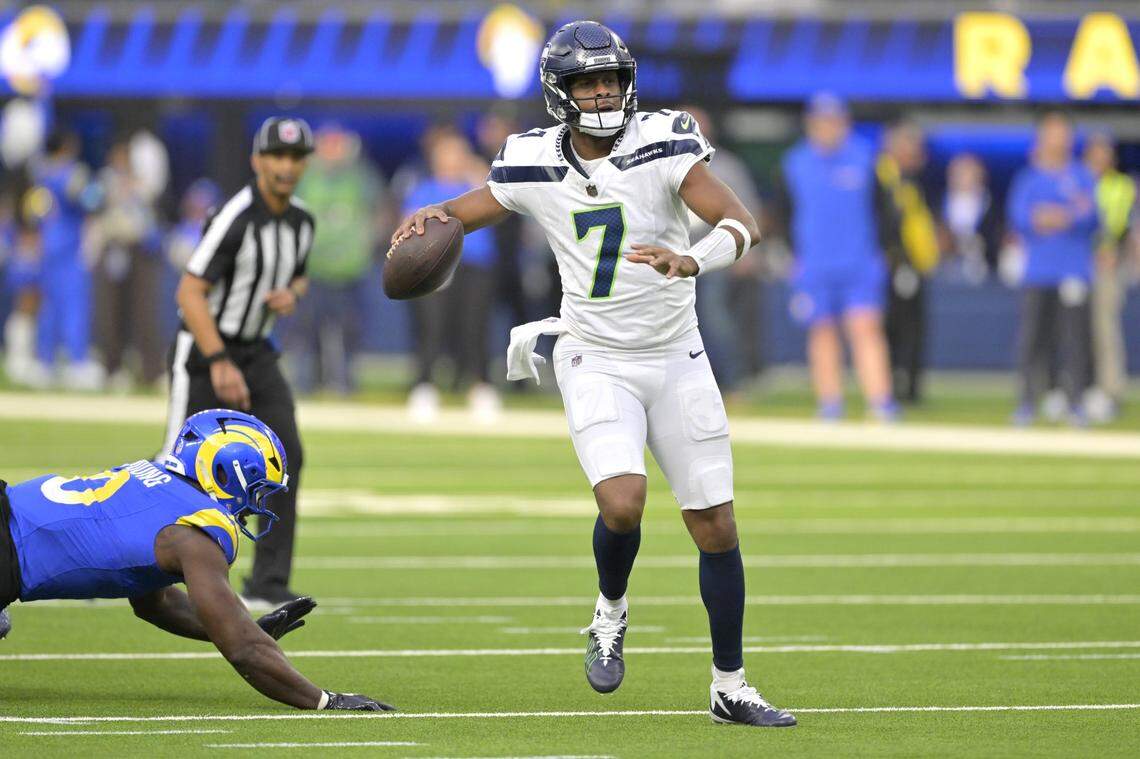Jan 5, 2025; Inglewood, California, USA; Seattle Seahawks quarterback Geno Smith (7) scrambles away from Los Angeles Rams linebacker Byron Young (0) and throws for a touchdown in the first half at SoFi Stadium. Mandatory Credit: Jayne Kamin-Oncea-Imagn Images