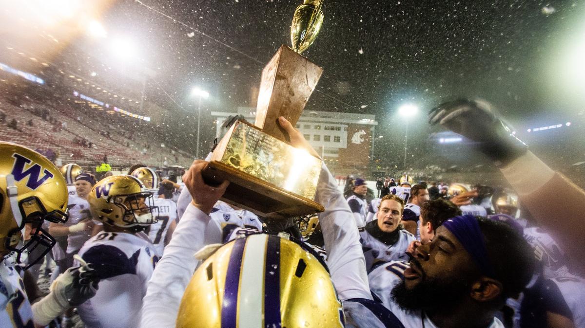 Washington quarterback Jake Browning (3) hoists the Apple Cup after the Huskies’ 28-15 win over WSU.