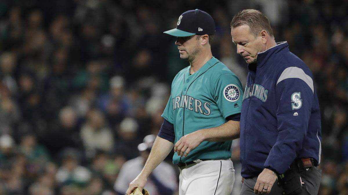 Seattle Mariners starting pitcher Wade LeBlanc, left, leaves with trainer Rob Nodine, right, during the fifth inning of the team’s baseball game against the Houston Astros, Friday, April 12, 2019, in Seattle. (AP Photo/Ted S. Warren)
