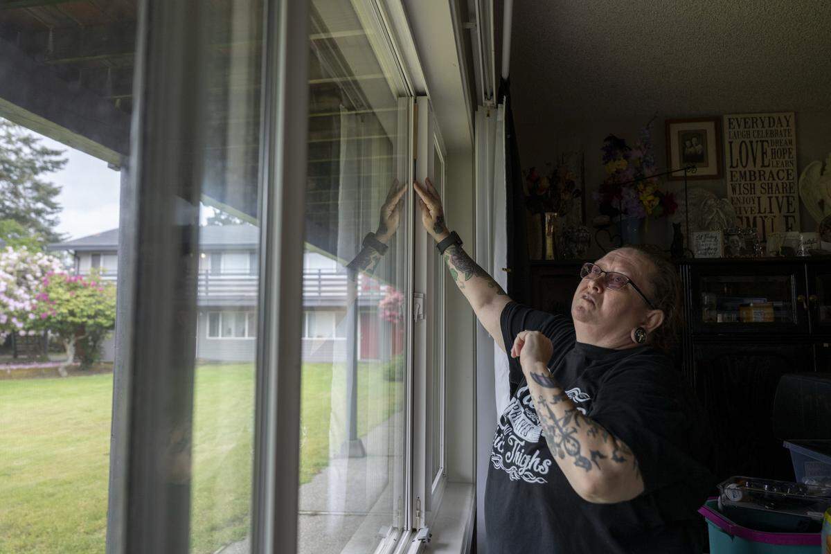 Melody Frazier pushes a dowel into place to help close gaps in her front window at Westside Estates, on Wednesday, May 13, 2026, in Tacoma, Wash.